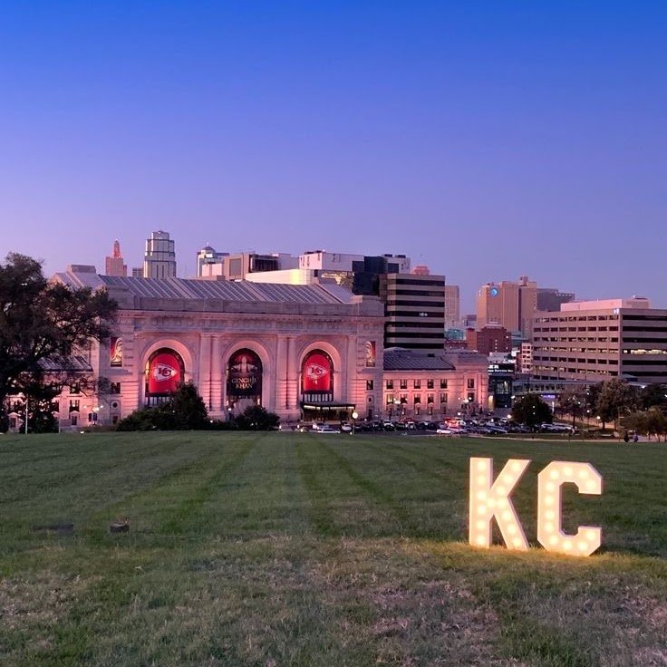 Union Station in Kansas City lit up at night, with the KC letters glowing on the lawn in front of it.
